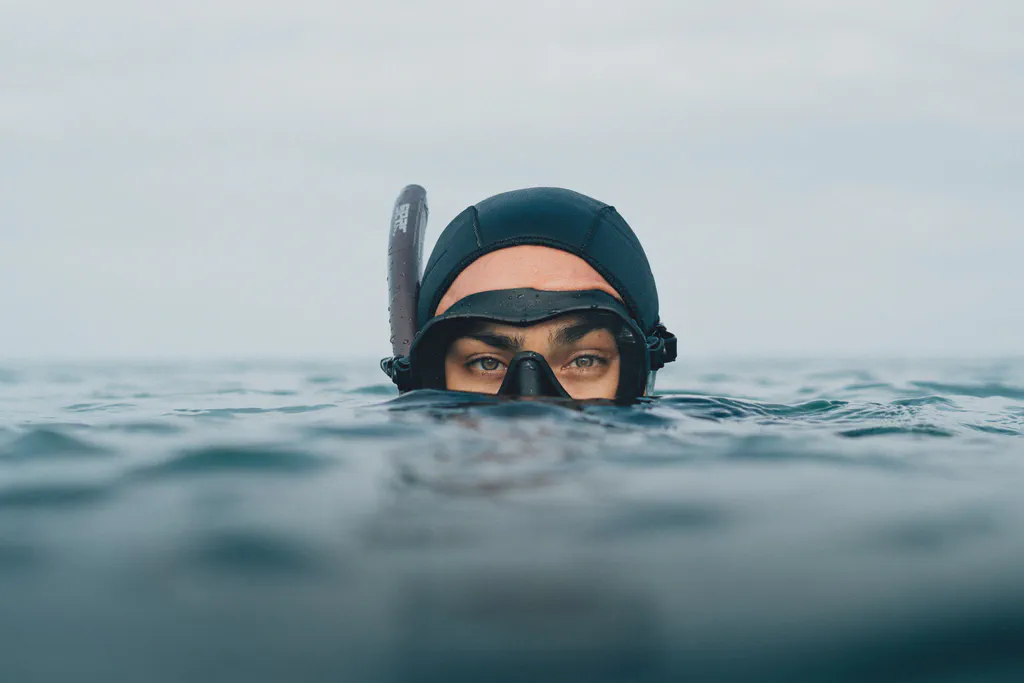 Léa Brassy émerge de l’eau, masque de plongée et bonnet noir sur la tête, tuba relevé sur le front.