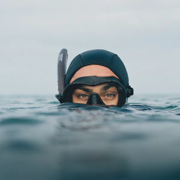 Léa Brassy émerge de l’eau, masque de plongée et bonnet noir sur la tête, tuba relevé sur le front.