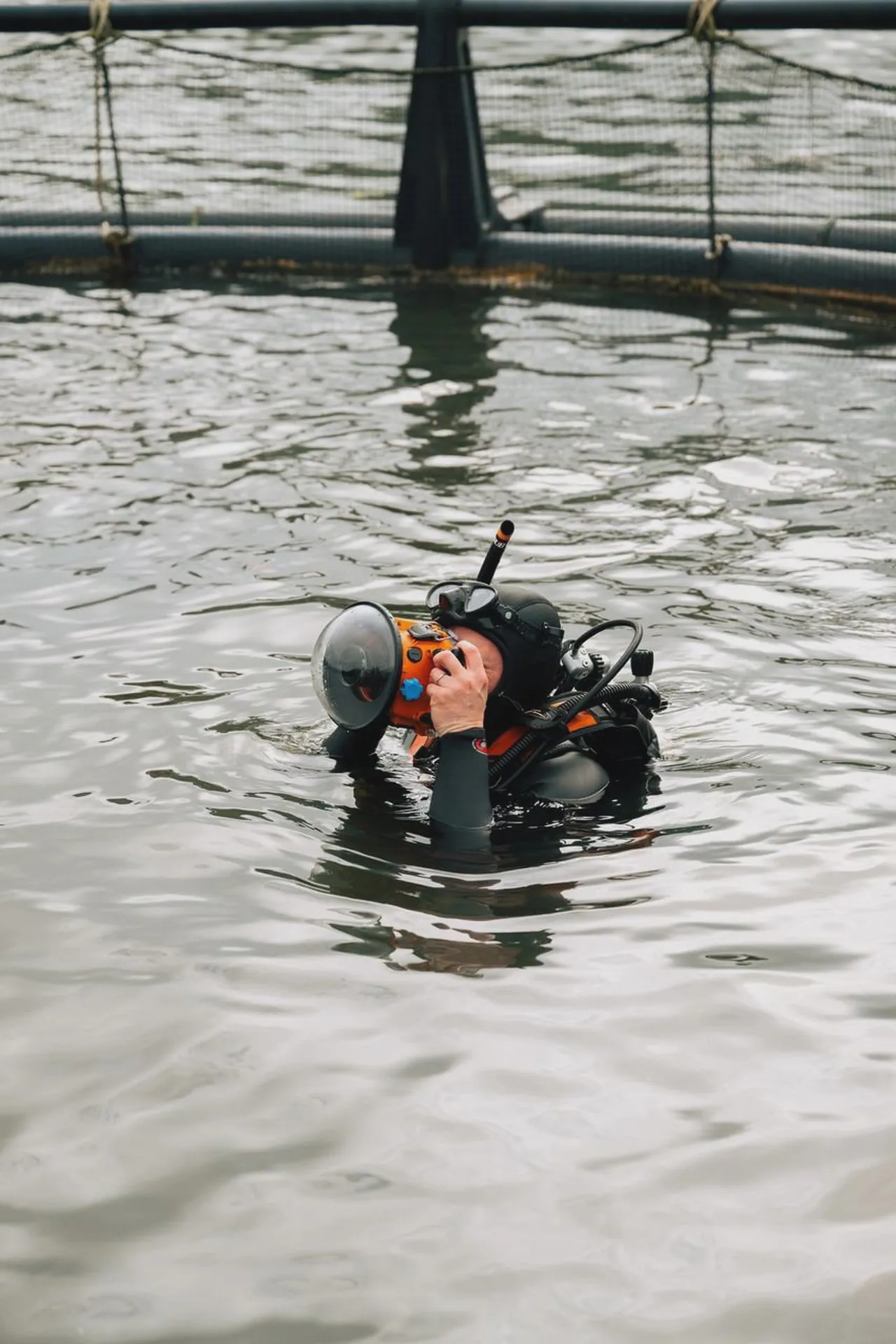 Yves Quéré plonge son appareil dans l’eau près d’un filet de parc à moules, masque et tuba sur la tête.