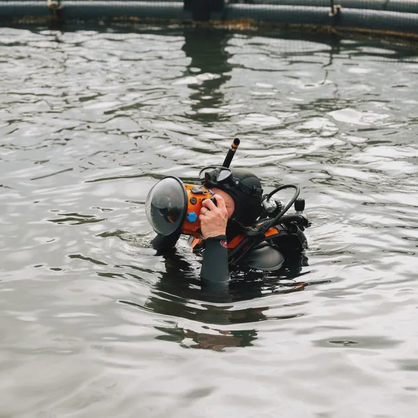 Yves Quéré plonge son appareil dans l’eau près d’un filet de parc à moules, masque et tuba sur la tête.
