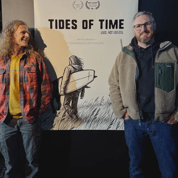 Yoann Renambot et Grégory Mignard posants devant l'affiche du film Tides of Time pendant le Brest Surf Film Festival